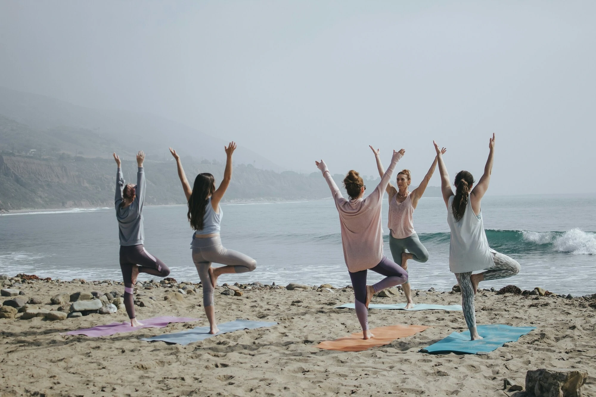 Image of five females doing Yoga on the beach